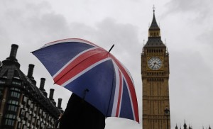 A woman holds a Union flag umbrella in front of the Big Ben clock tower and the Houses of Parliament in London