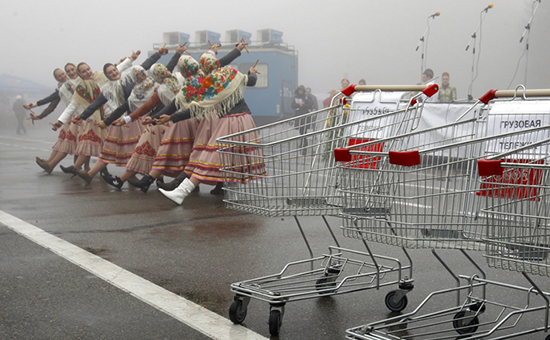 Women dressed in folk costumes dance behind empty shopping trolleys during a food fair in Stavropol