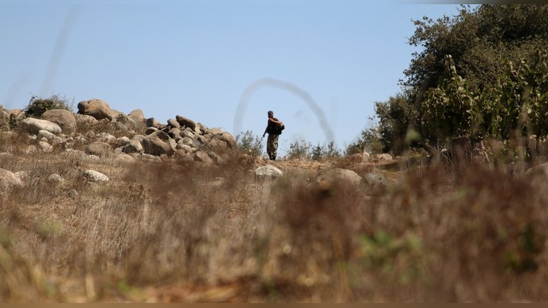 A rebel fighter walks with his weapon in Jubata al-Khashab